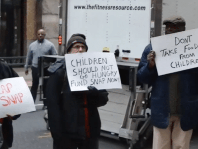 People hold signs protesting SNAP cuts.